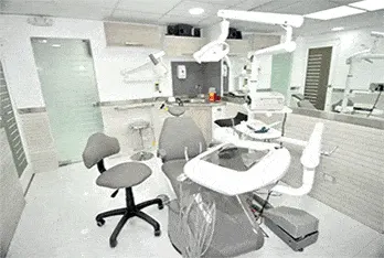 Consultorio 2 con sillón dental gris y equipo de rayos X