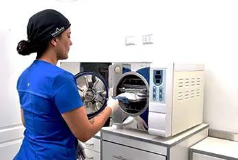 Asistente cargando instrumental en el autoclave del área de esterilización